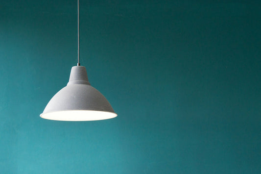 Pendant lamp glowing against a teal wall